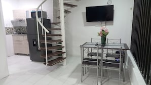 Una cocina moderna con microondas, refrigerador y comedor con mesa y sillas.