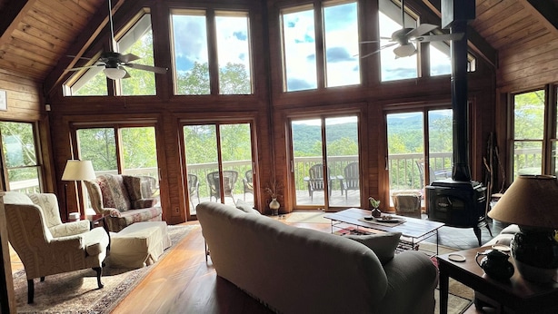 A spacious living room with a high ceiling and large windows, wooden flooring, and a fireplace. - Vista Greystone Lodge-Incredible view!! Streaming tvs! Wifi! Private! Sleeps 10! (Talking Rock)