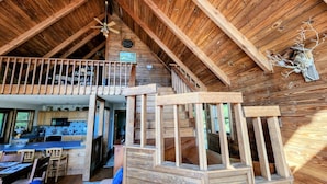 A rustic wooden cabin interior with a kitchen, dining area, and a loft bedroom. - Vista Greystone Lodge-Incredible view!! Streaming tvs! Wifi! Private! Sleeps 10! (Talking Rock)