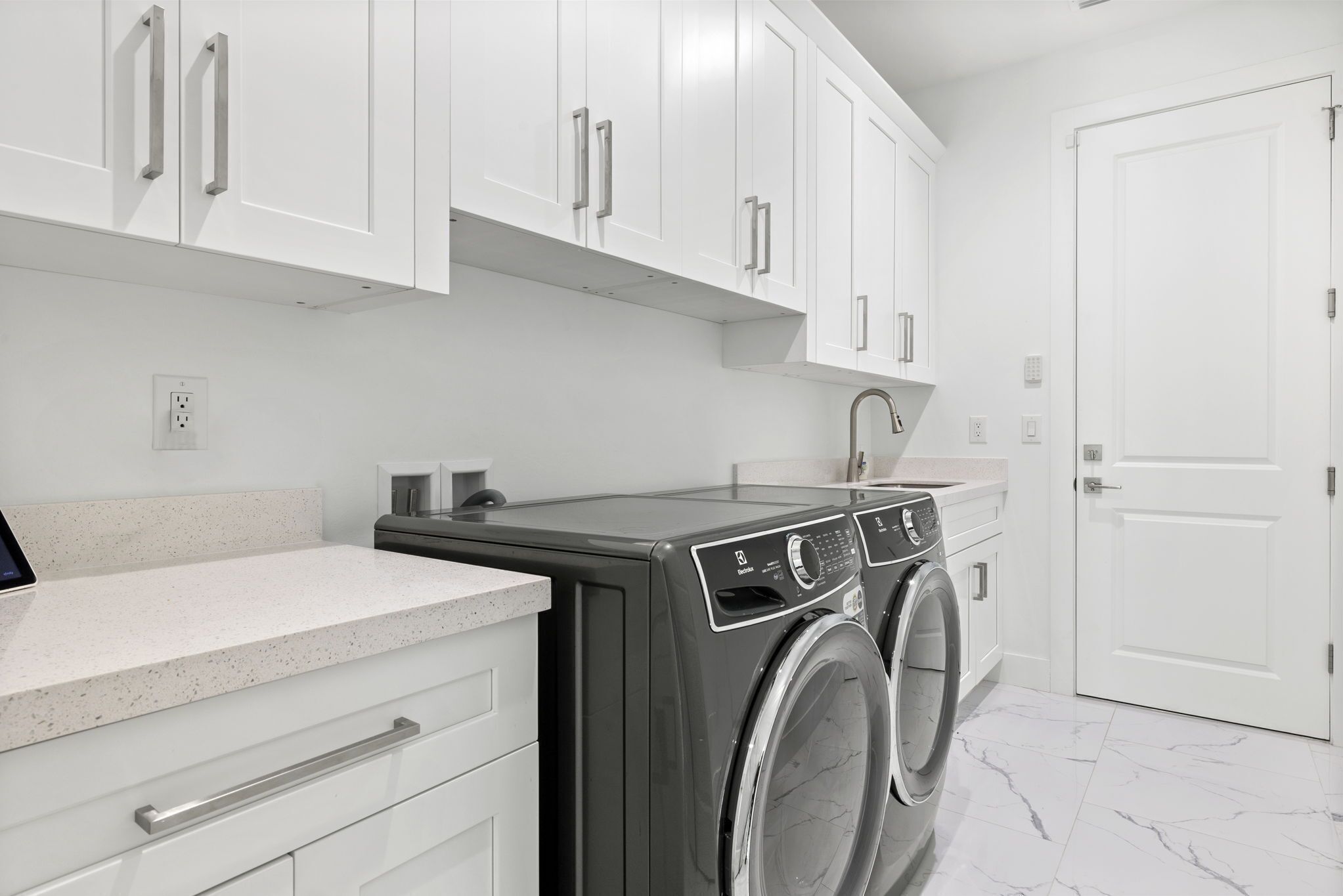 A modern laundry room with a washing machine, a dryer, and a countertop.