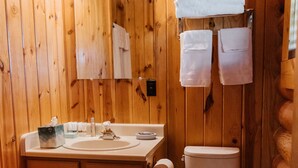 Un baño con paneles de madera, un lavabo, un espejo y un inodoro.