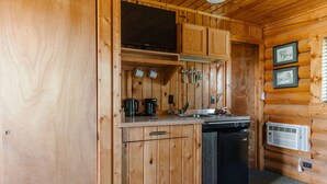 Cocina de cabaña de madera con estufa, cafetera y refrigerador.