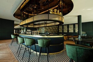 Un espace bar à la disposition circulaire, doté de tabourets de bar et d’un coin salon avec un sol à motifs.