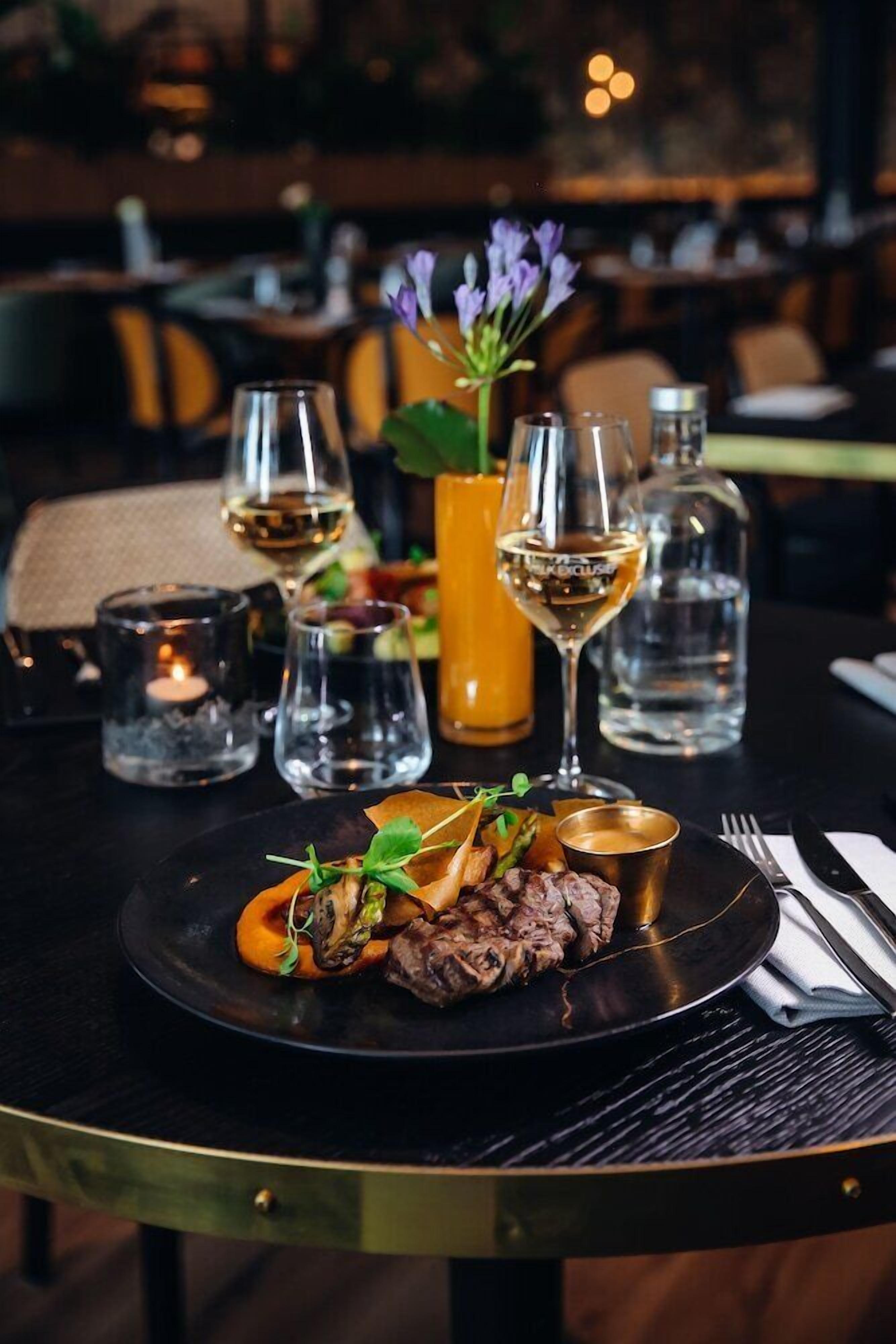 Une table à manger avec une assiette de nourriture, des verres et une bougie.