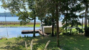 Una propietat a la vora d'un llac amb un moll, un edifici petit i una zona enjardinada amb pedres i plantes.