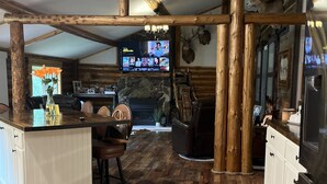 Una cocina rústica con pisos de madera, chimenea de piedra y televisor montado.