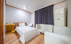 A hotel room with a bed, a desk, a chair, a sofa, and a wardrobe. - Donghae Lisa Hotel (Donghae)