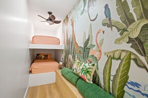 Een kamer met een stapelbed, een plafondventilator en een muurschildering van jungle dieren.