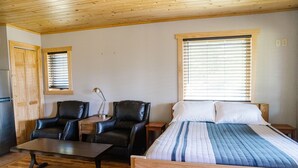 Een kamer met een bed, twee stoelen, een tafel en een raam.