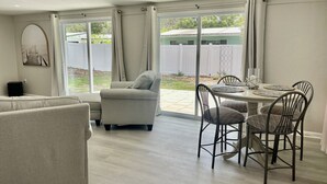 En rummelig opholdsstue med sofa, lænestol og spisebord med stole.