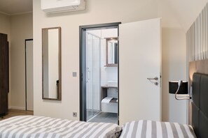 A hotel room with a bed, a mirror, a door leading to a bathroom, and a wall-mounted air conditioner. - Hotel & Restaurant Beisenbusch (Bottrop)