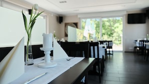 Un coin repas avec une table mise pour deux, agrémentée d’une bougie blanche, d’un vase en verre contenant une seule fleur, ainsi que d’une fourchette et d’un couteau posés sur la table.