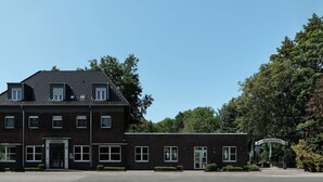 Un bâtiment à deux étages, construit en briques, avec un toit plat, une entrée centrale et une enseigne indiquant « Biergarten ».