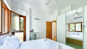 Una habitación de hotel con cama, escritorio, silla, espejo y una puerta que da a otra habitación.