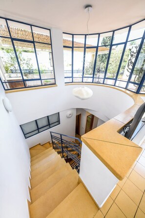 A spacious interior with a curved staircase, large windows, and a high ceiling. - Penthouse • Terrace & City Views by SeaNRent (Tel Aviv-Yafo)