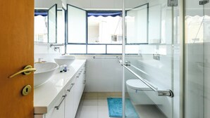 Un baño moderno con cabina de ducha de vidrio, un lavamanos blanco y un inodoro.