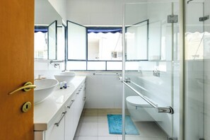 A modern bathroom with a glass shower enclosure, a white sink, and a toilet.