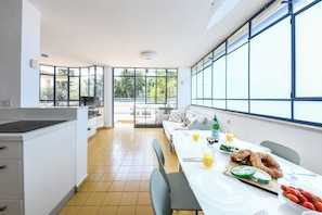 A modern kitchen with a dining area, large windows, and a view of the outdoors. - Penthouse • Terrace & City Views by SeaNRent (Tel Aviv-Yafo)