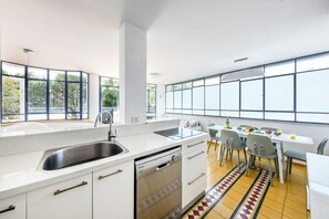 Une cuisine moderne équipée d’un lave-vaisselle, d’un évier et d’un coin repas avec des chaises et une table.