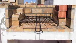 En grill av tegelsten med ett metallgaller, omgiven av stenmurar.