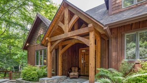 Une cabane en bois avec un porche en pierre, de grandes fenêtres et un porche abrité.