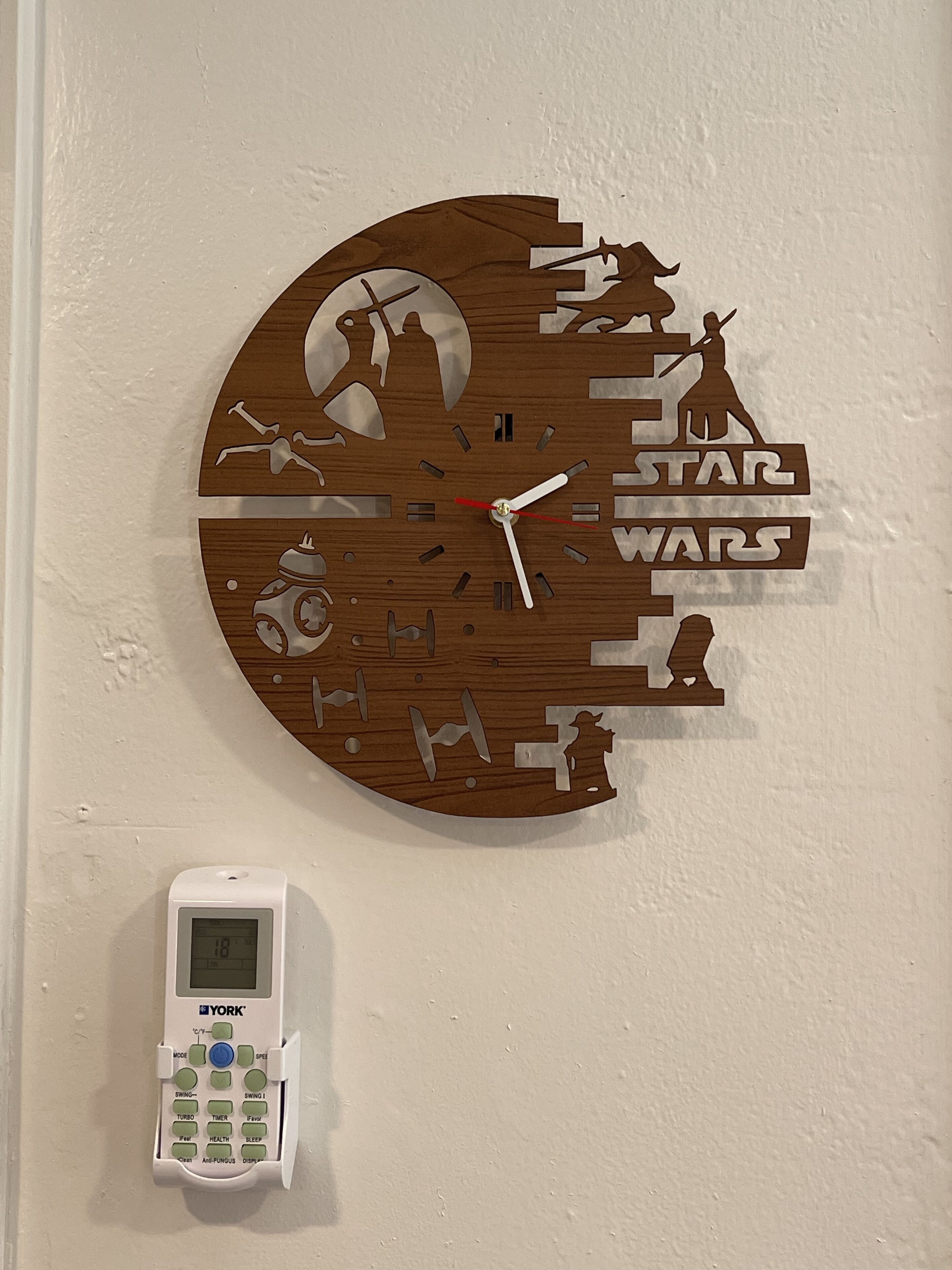 Une horloge murale sur le thème de Star Wars, avec un thermostat numérique placé en dessous.