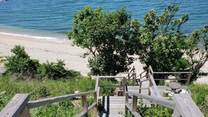 Eine Holztreppe führt zu einem Strand mit Blick auf das Meer.