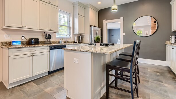 A modern kitchen with white cabinetry, granite countertops, and a central island with seating. - LoHi Retreat, Walk to Downtown, Game Room, Huge Backyard, Sleeps 12, Garage (Denver)