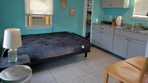 A bedroom with a bed, bedside table, lamp, and a window with blinds.