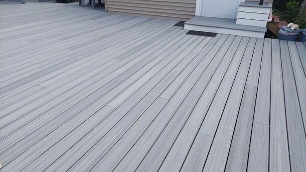 A wooden deck with a metal stairway leading to a door.