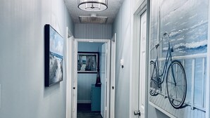 A hallway with a wooden floor, a ceiling fan, and a bicycle mounted on the wall. - Peaceful Sunshine Cottage walk to waterfront family friendly  (Southport)