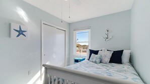 A bedroom with a bed, a window, a door, and a star decoration on the wall. - Peaceful Sunshine Cottage walk to waterfront family friendly  (Southport)