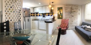 A modern kitchen with white cabinets, a refrigerator, and a dining area with a glass table and chairs. - 2CP1-C APARTAMENTO DUPLEX EN CARTAGENA (Cartagena)