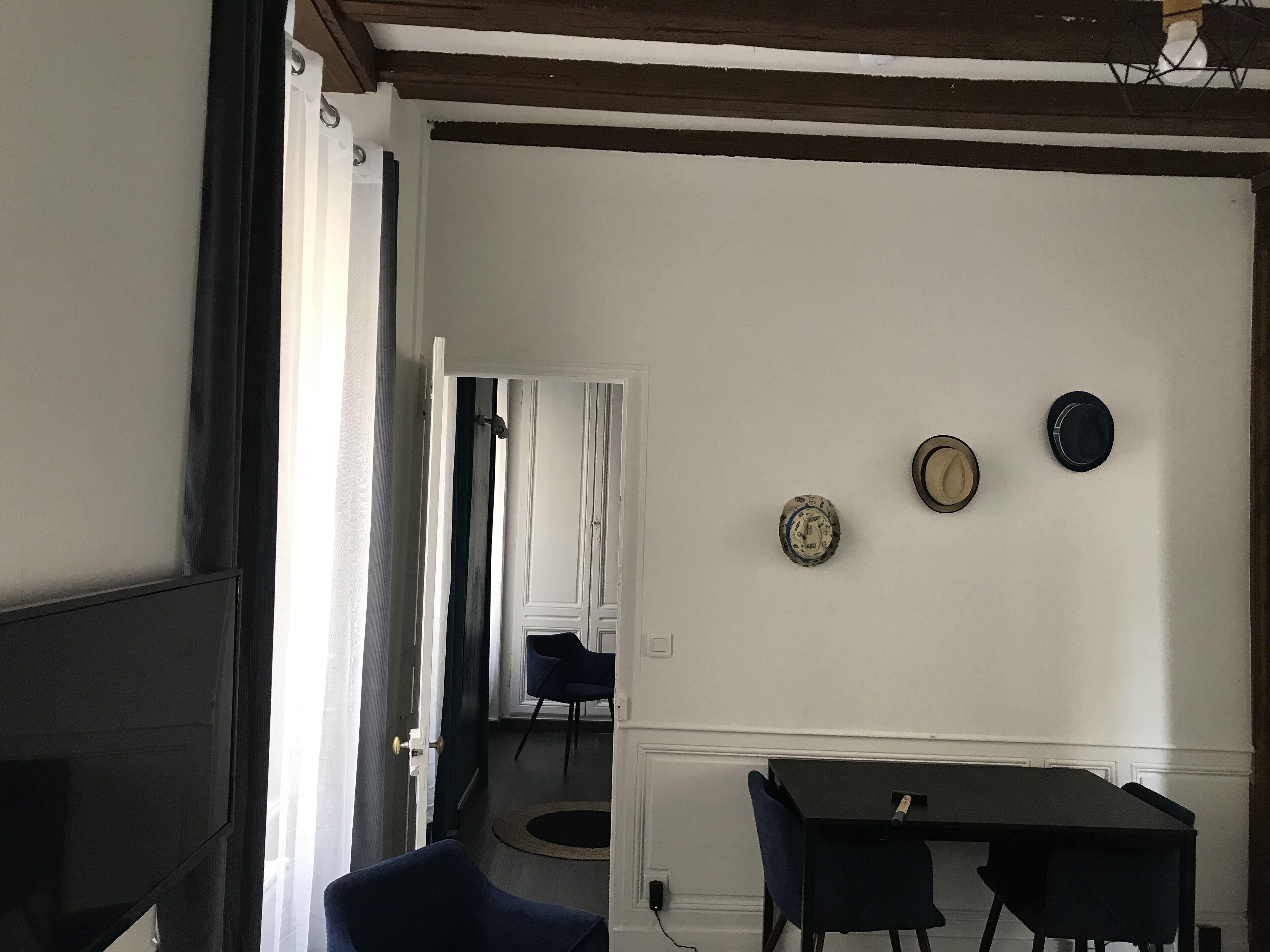 A room with a dining table and chairs, a door leading to another room, and a wall with three decorative plates.