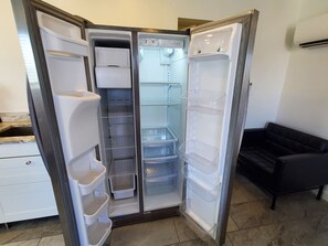 A corner refrigerator with multiple compartments, including a freezer, a main compartment, and a water dispenser.