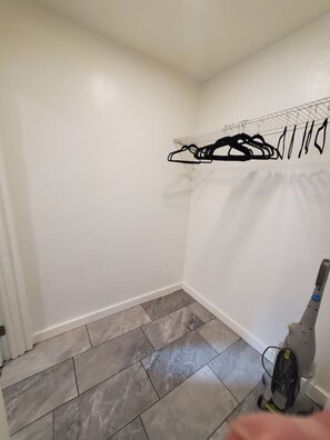 A small, clean room with grey tiled flooring, a white radiator, and a vacuum cleaner.