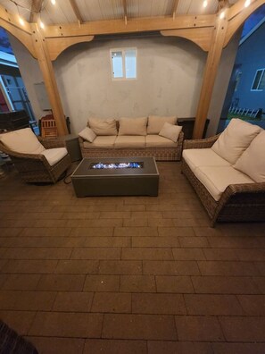 An outdoor seating area with wicker furniture and a fire pit.
