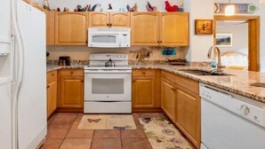 A compact kitchen with wooden cabinets, a white stove, and a microwave.