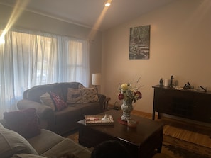 A living room with a sofa, a coffee table with a vase of flowers, a lamp, and a painting on the wall.