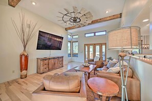 A spacious living room with a large TV, wooden furniture, and a ceiling fan.