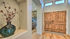Un corridoio con una porta in legno, un vaso con fiori secchi e una parete in pietra sullo sfondo.