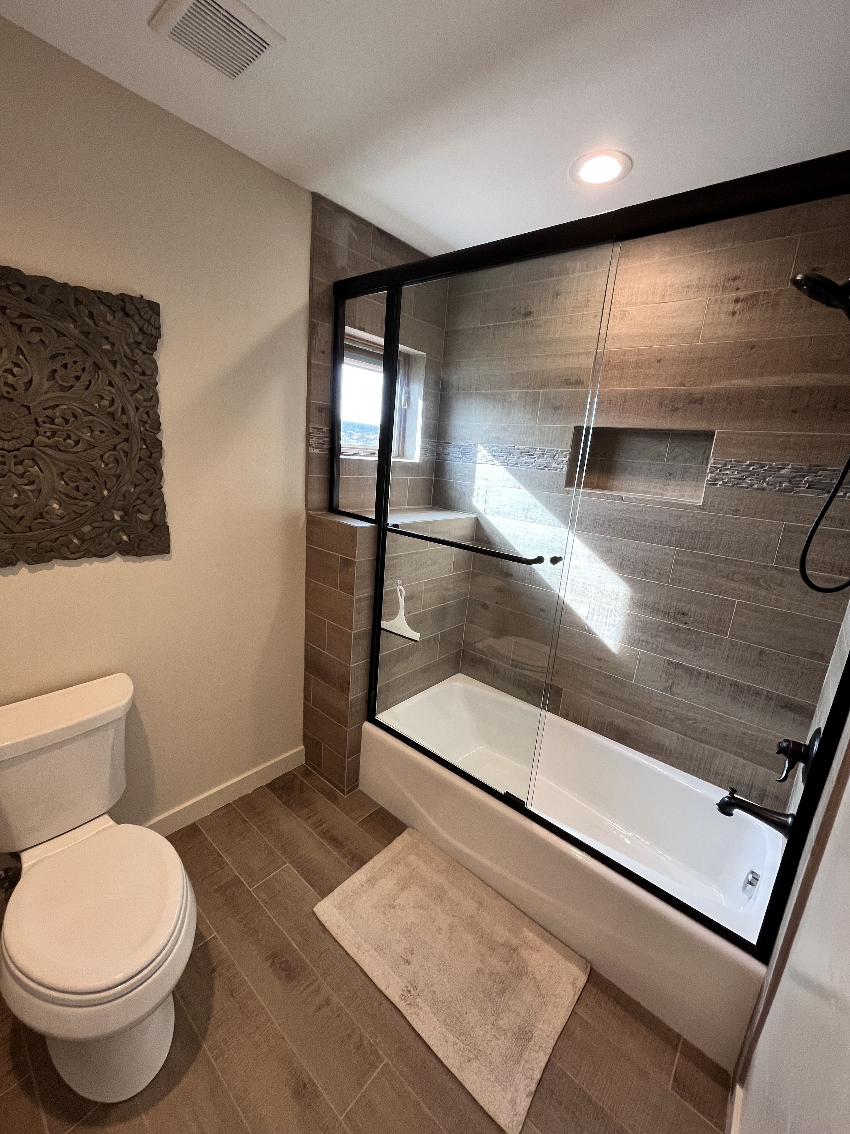 A modern bathroom with a glass-enclosed shower, a toilet, and a built-in sink.