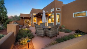 Una casa moderna con patio, arredi da esterno e un giardino ben illuminato.