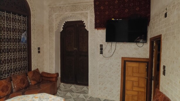 Une pièce avec un canapé, un téléviseur fixé au mur, une porte à motifs et un mur à motifs.