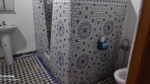 Une salle de bain avec des carreaux décorés, un lavabo, des toilettes et un espace douche.