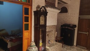 Une chambre de style traditionnel, avec une porte en bois, un grand miroir, une horloge murale et un buffet orné de motifs.