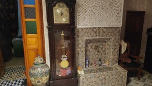 Une pièce au décor traditionnel, avec une grande horloge en bois, un meuble décoratif et un papier peint à motifs.