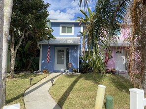 A two-story house with a blue exterior, a white front door, and an American flag.