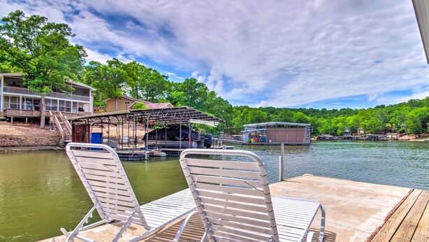 A dock with two metal chairs and a covered area with a railing. - Furnished Deck, Dock! Lake of the Ozarks Oasis (Sunrise Beach)