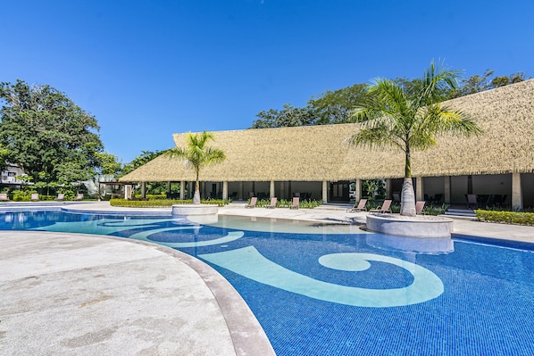 A swimming pool with a tropical design, surrounded by lounge chairs and palm trees.